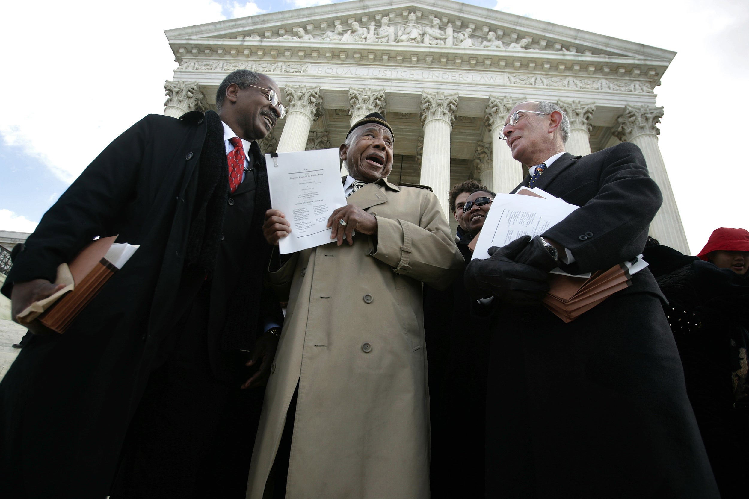 Charles Ogletree, Otis Clarke, and Michael Hausfeld outside Supreme Court in 2005. Clarke, a Tulsa riot survivor who was 102 at the time of this picture, looks emotional as he holds up the court brief.