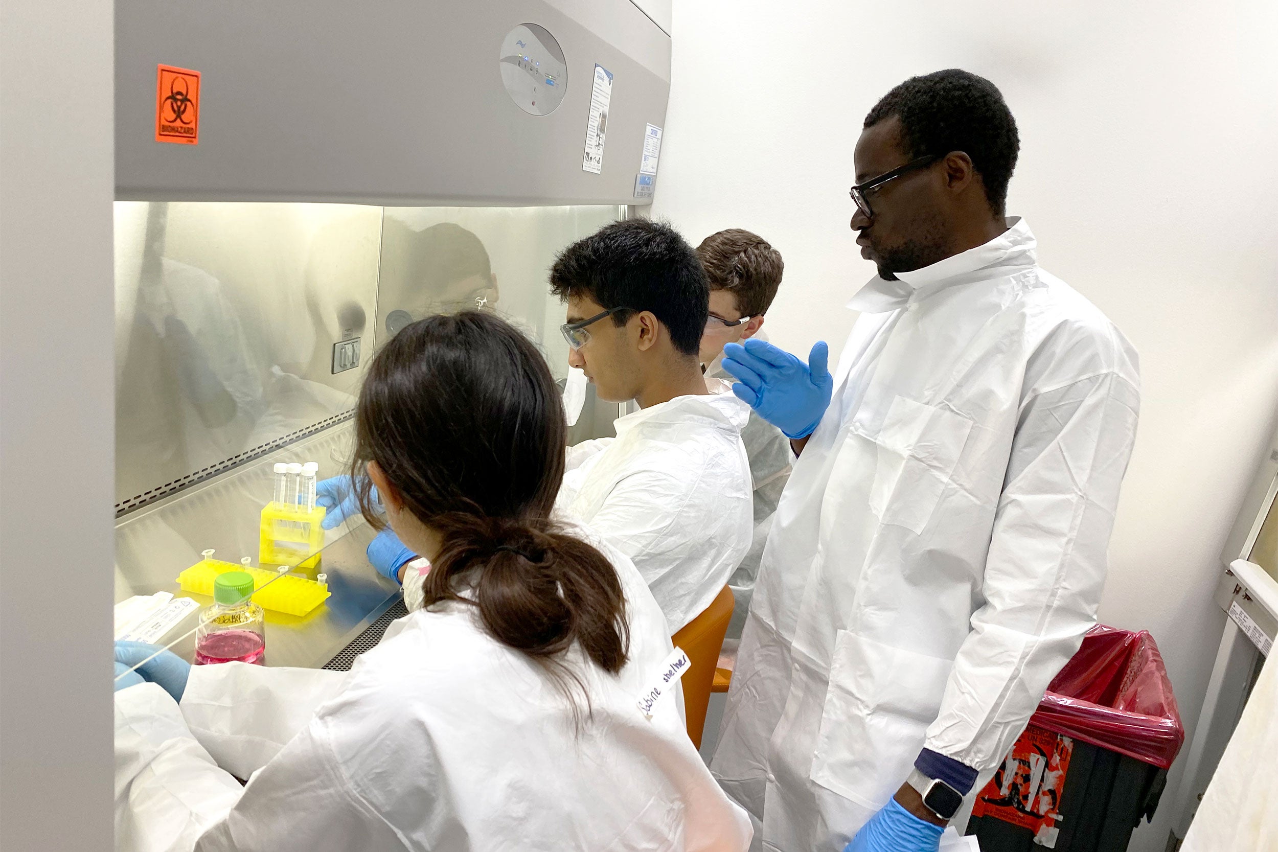Postdoc instructioning high school students in a lab.