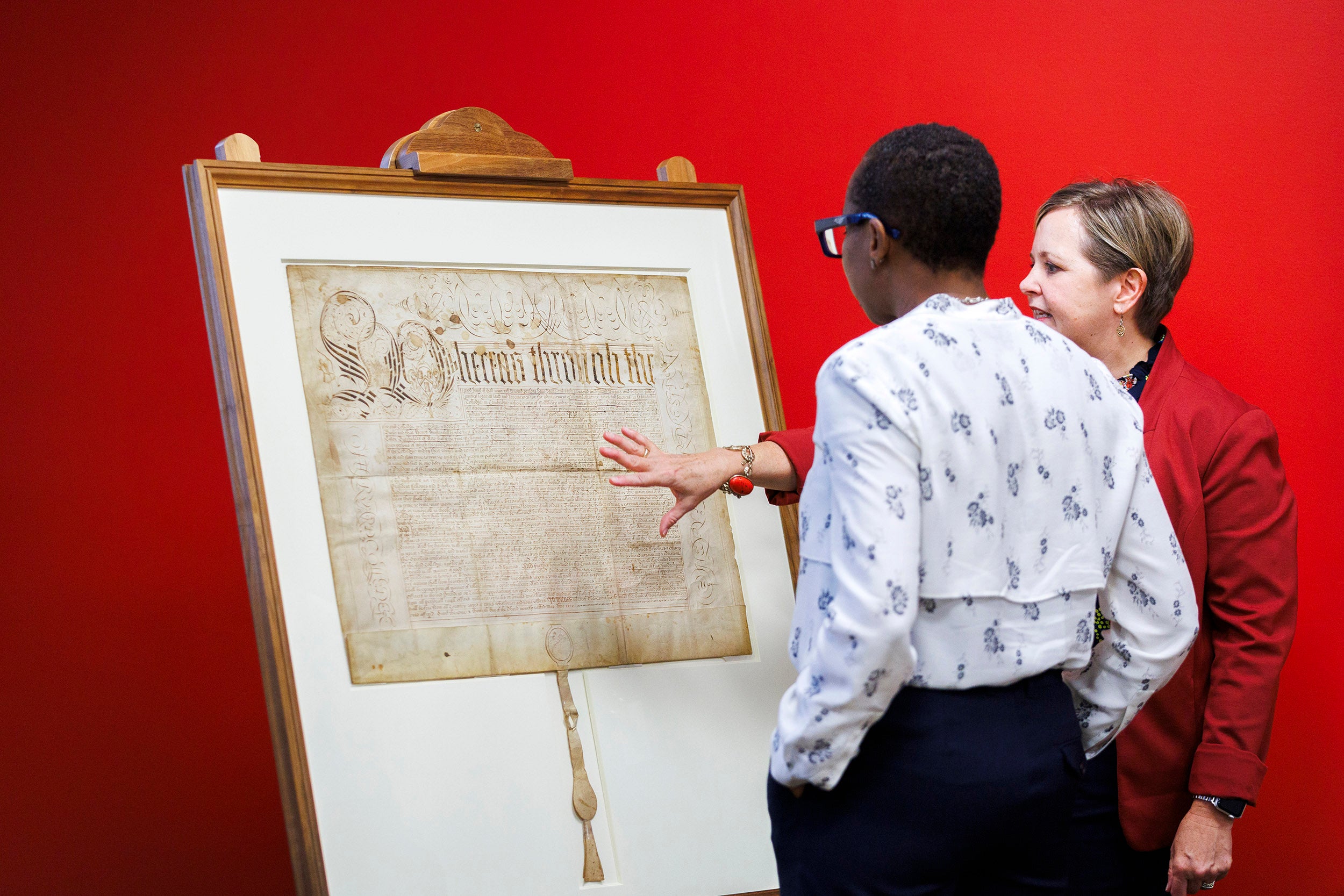 Archivist Virginia Hunt shows Harvard President Claudine Gay the Harvard Charter of 1650.