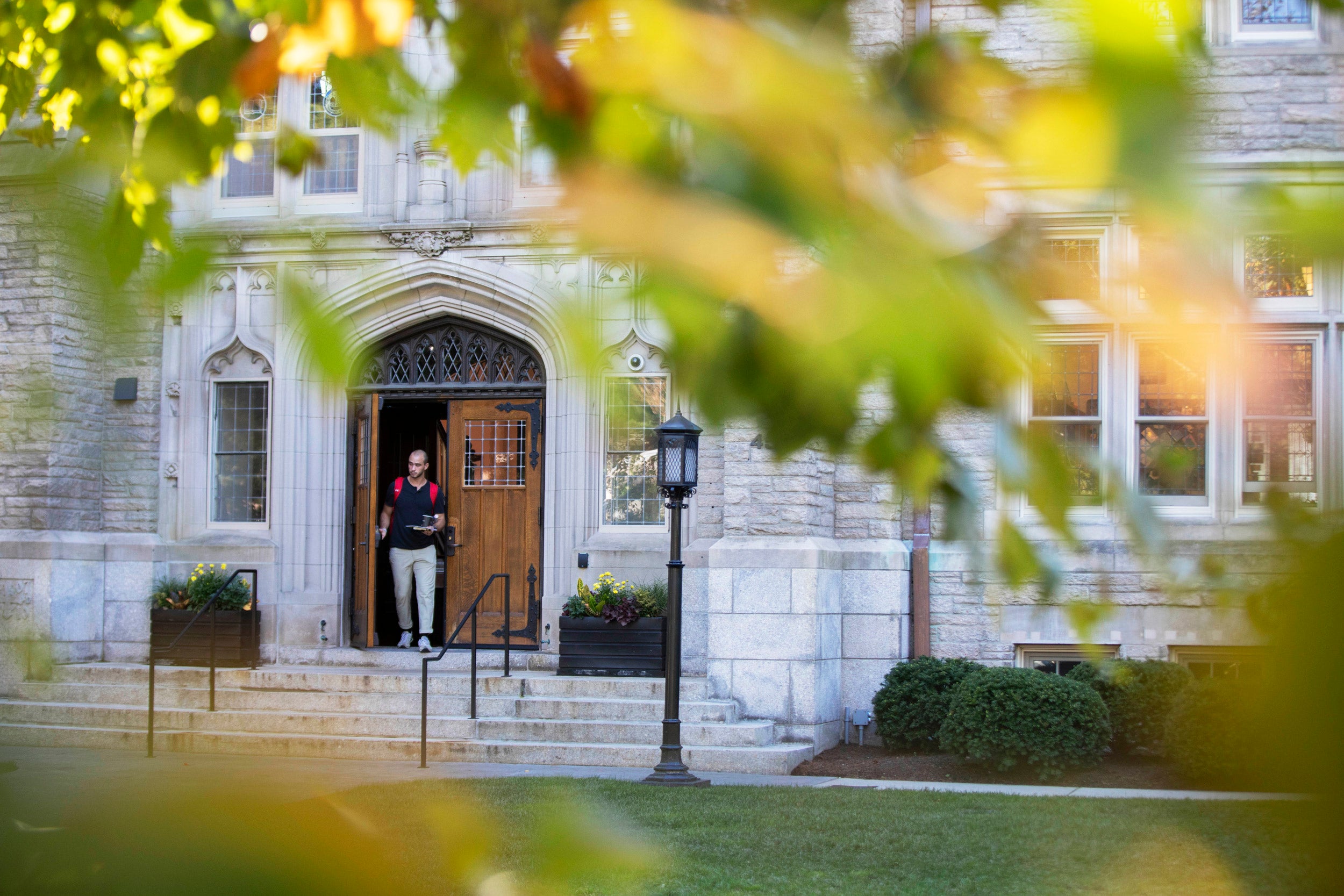 Sunlit foliage frames the entrance to Swartz Hall at the Divinity School.