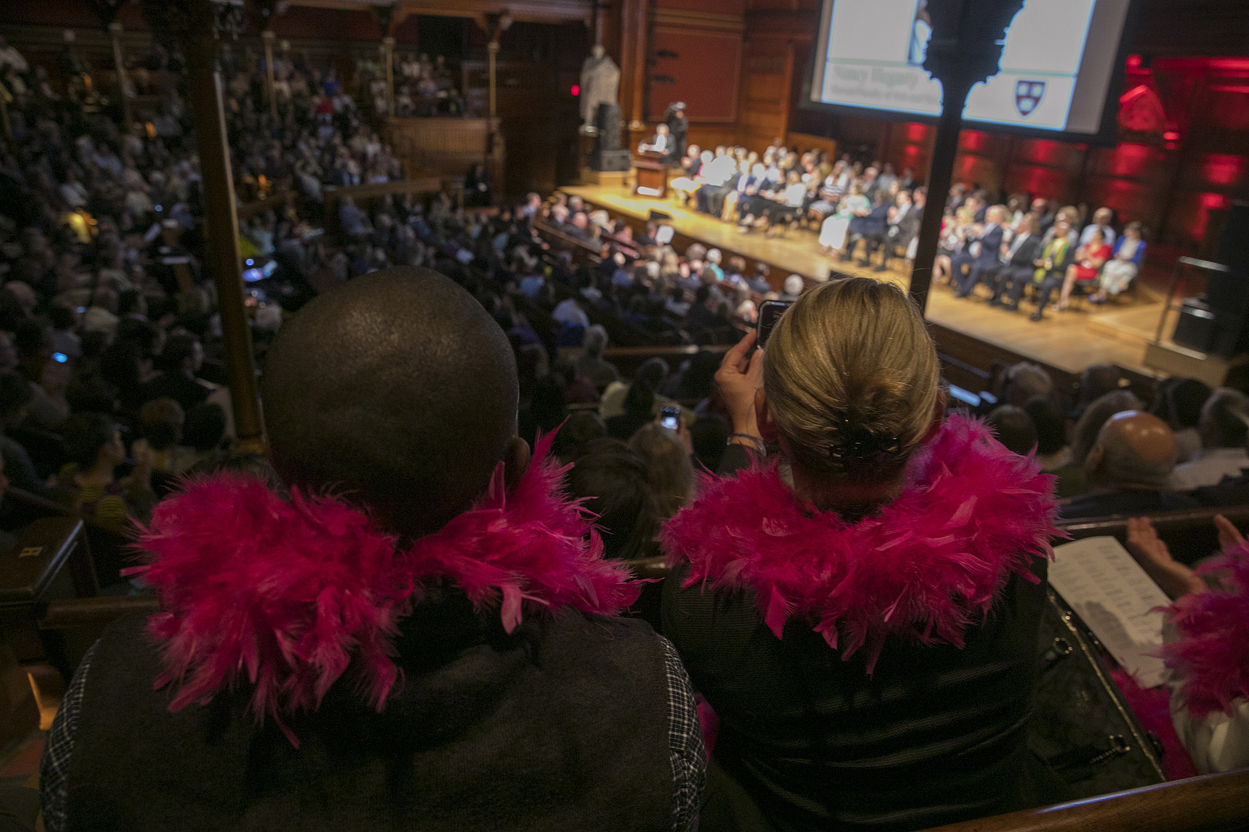 Two spectators wearing pink feather boas