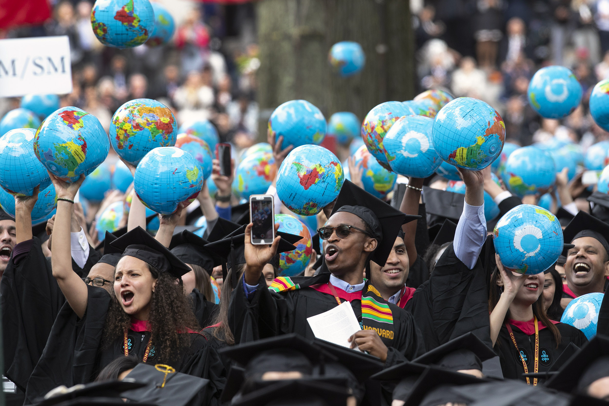 Kennedy School of Government graduates wave inflatable globes.