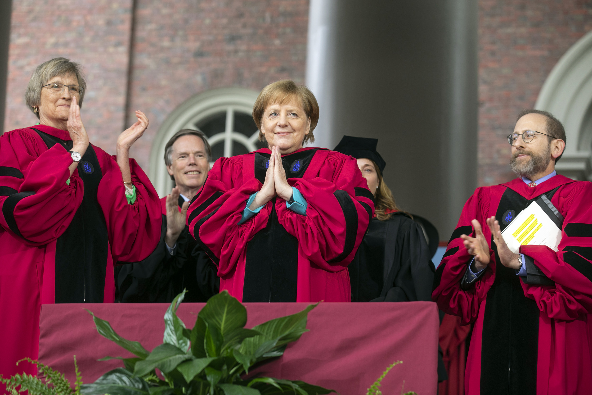 Angela Merkel holds her hands in a prayer acknowledging the applause after receiving her honorary degree.