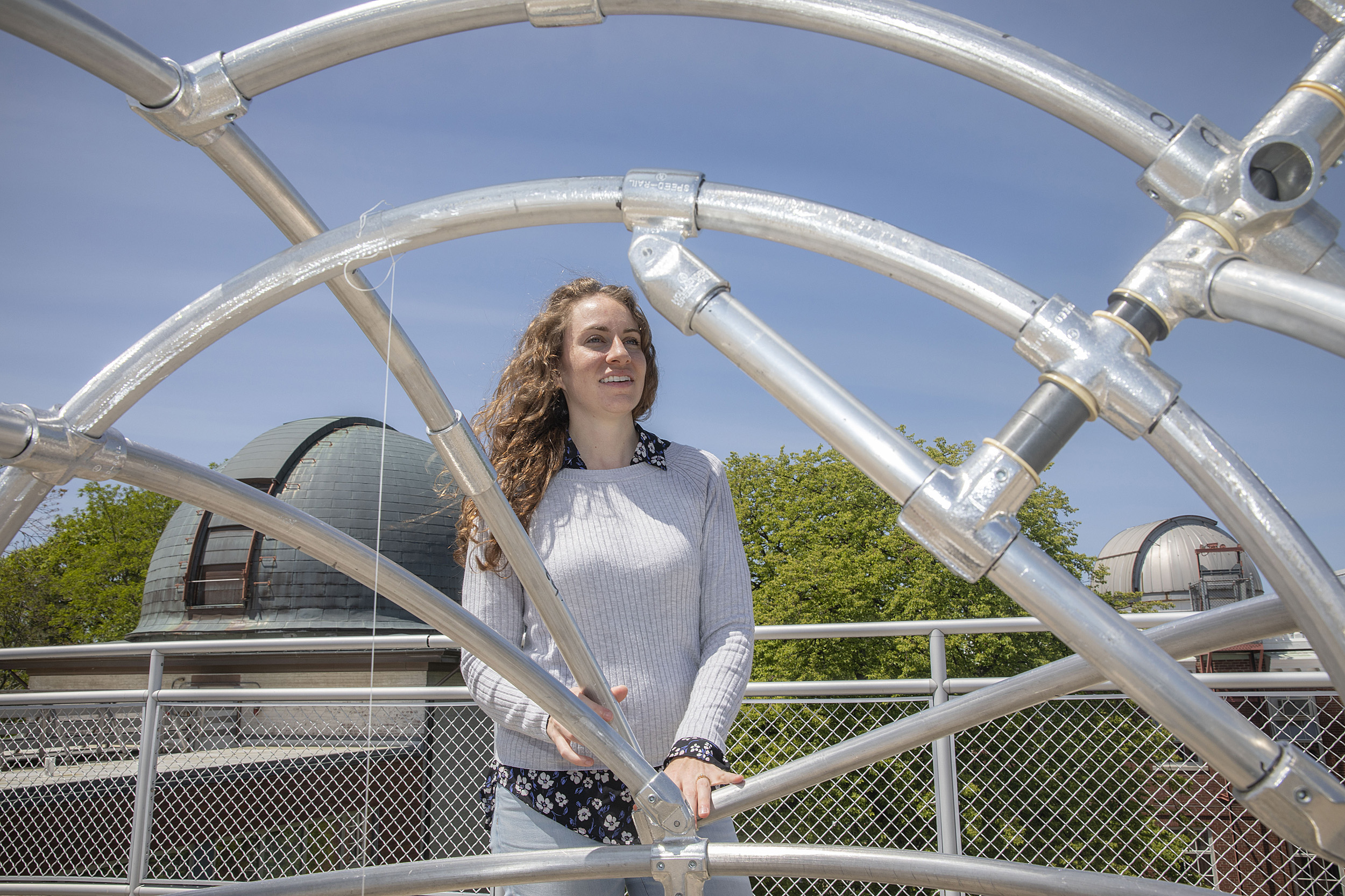 Center for Astrophysics astronomer Laura Kreidberg framed by a metal structure