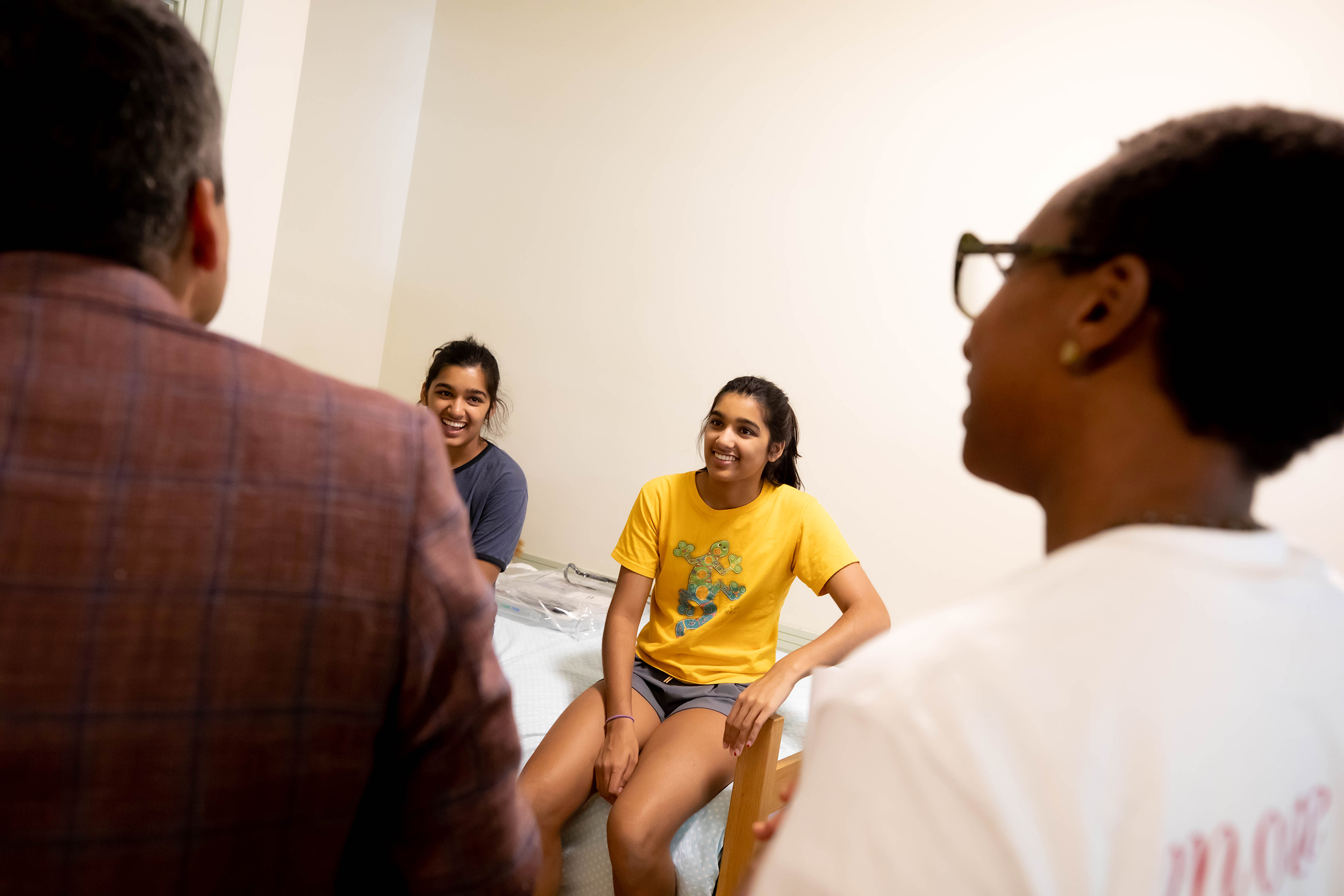 Twins Anisa (left) and Sirina Prasad chat with Deans Rakesh Khurana and Claudine Gay in Sirina’s room.