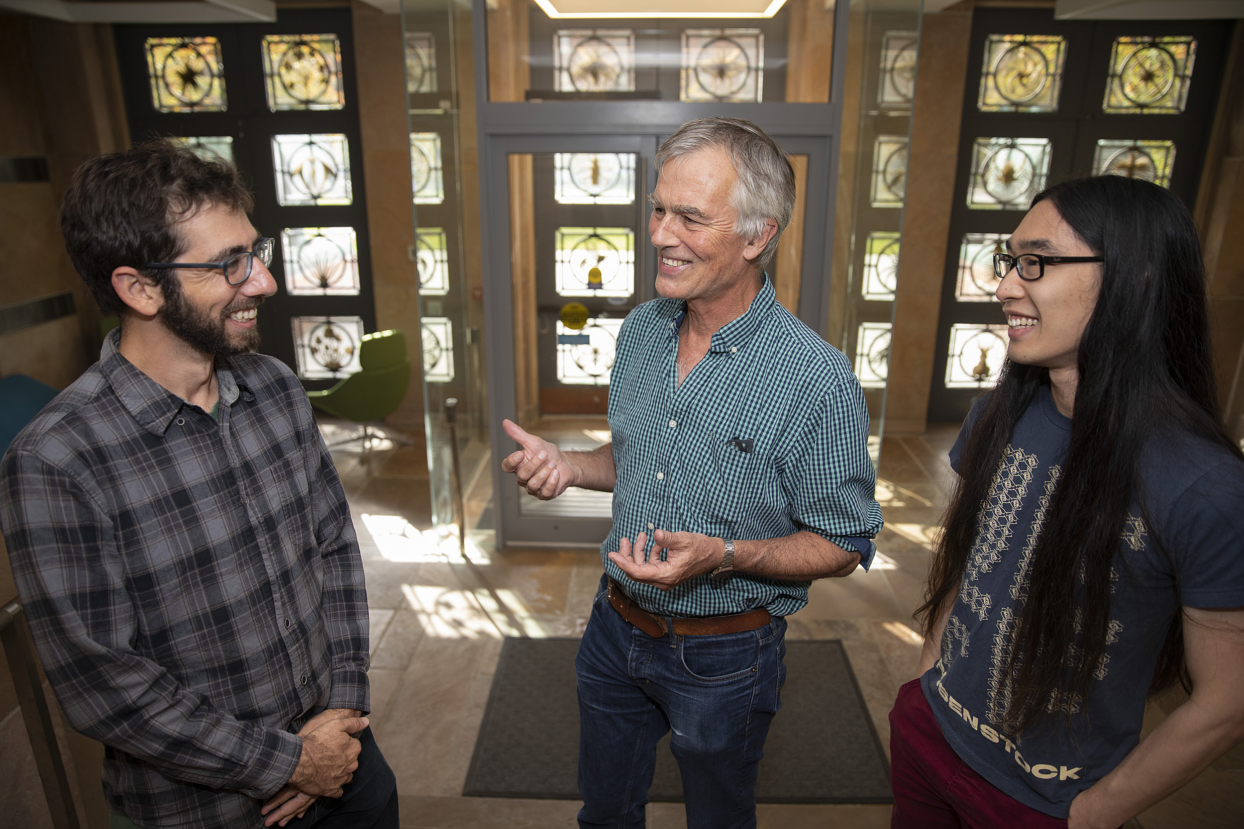 James Mallet (blue shirt) and colleagues Nate Edelman (plaid shirt) and Michael Miyagi (long hair) are the authors of a study that butterfly genomes inside the biology labs.