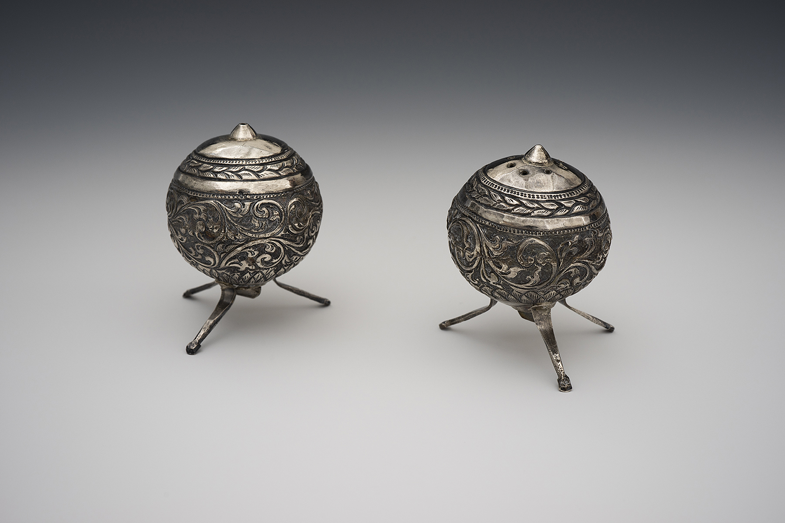 Spherical silver salt and pepper shakers with intricate designs