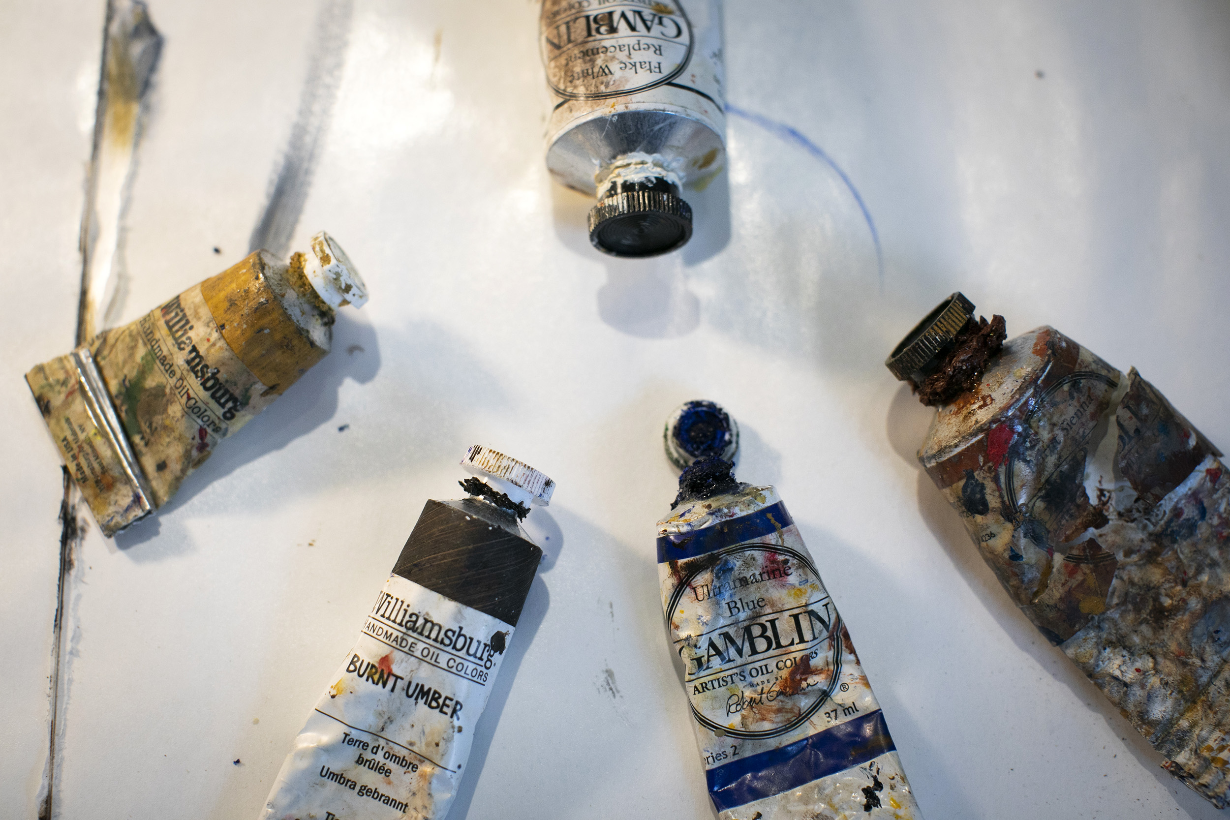 Five oil paint tubes lay on a table.