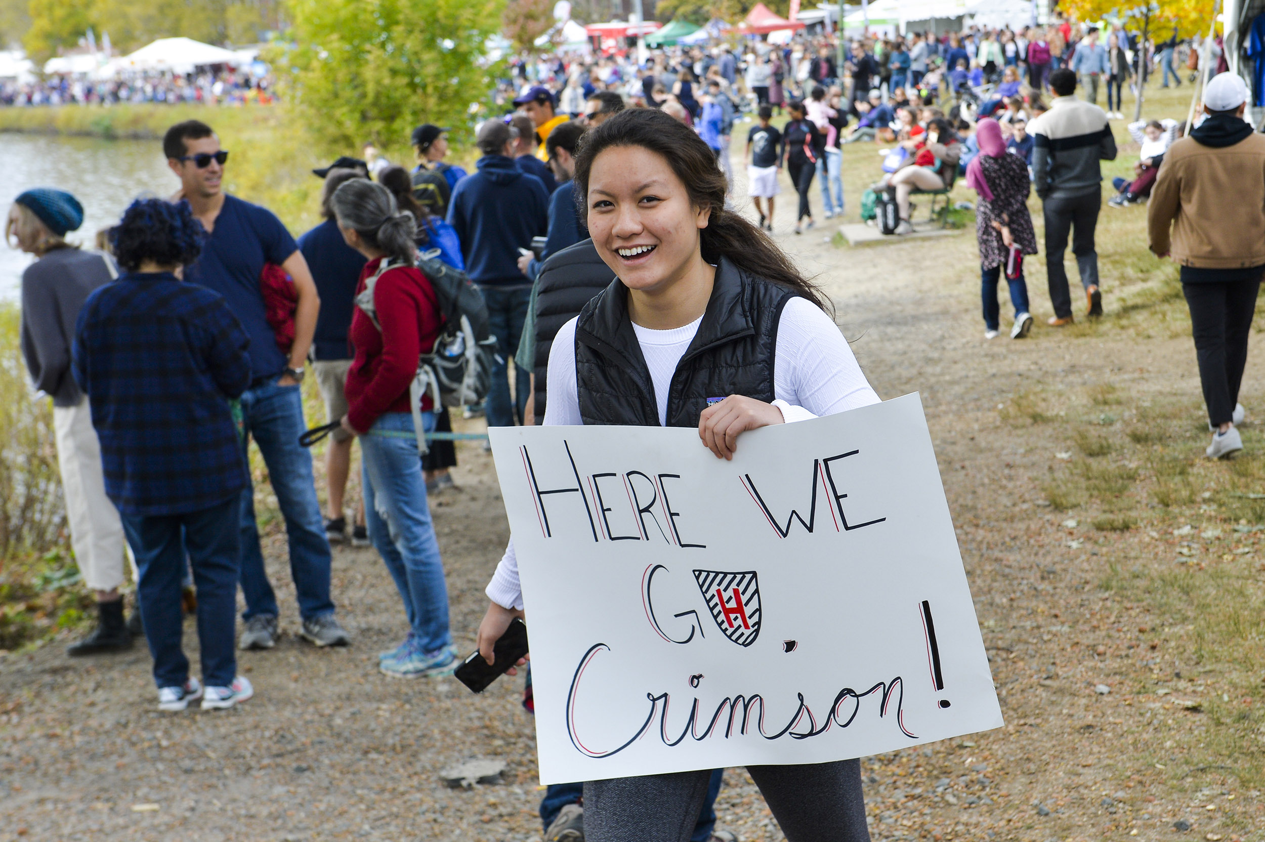 Student Athena Ye holds a sign "Here we go Crimson" during Head of the Charles weekend.