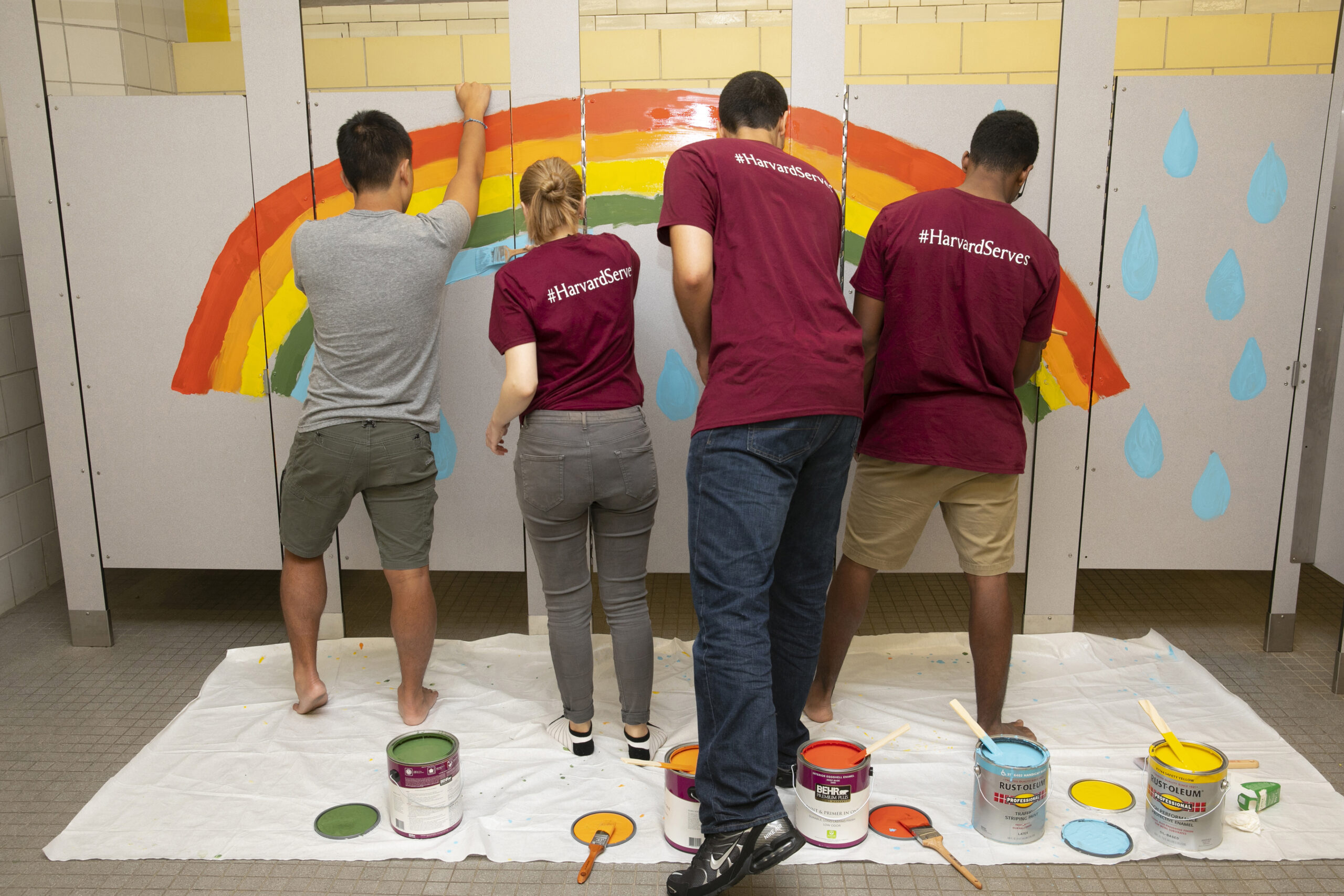 Students paint bathroom stall doors.