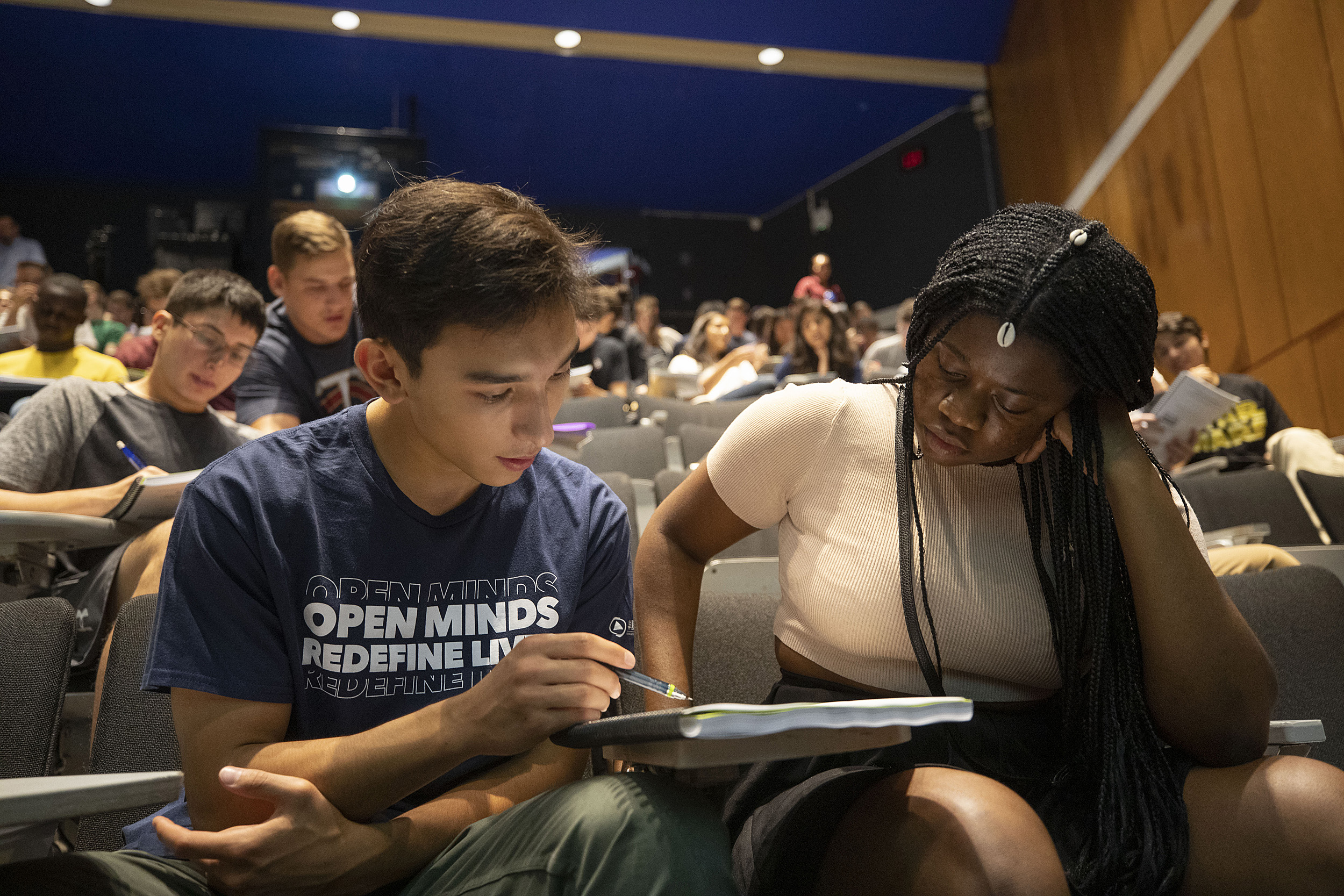 Two students studying together in a lecture hall.