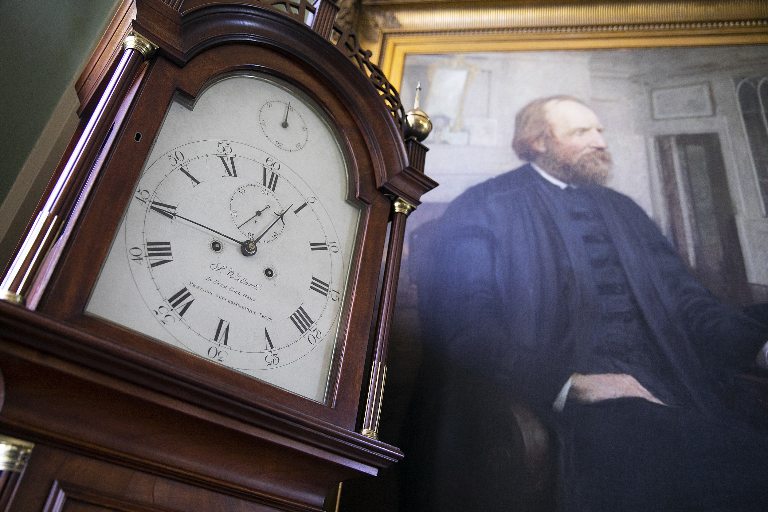Clock next to a portrait.
