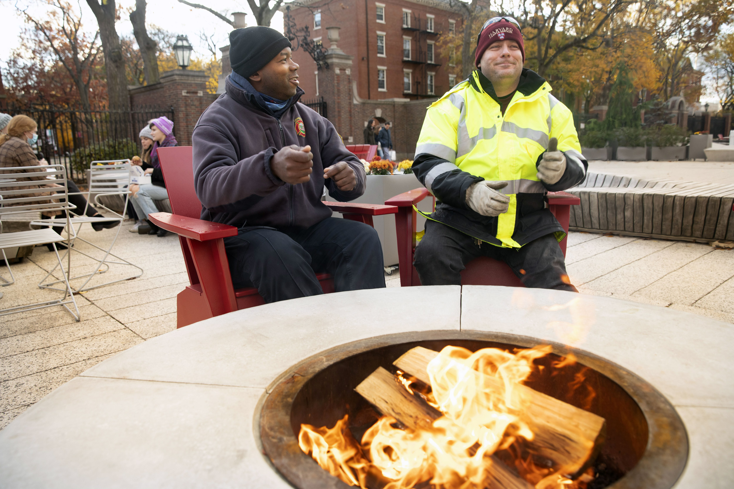 Cambridge firefighter John Bernard (left) and Mike Paszkiewicz of Facilities Maintenance Operations and Campus Services warm their hands over a fire pit at the Science Center Plaza.