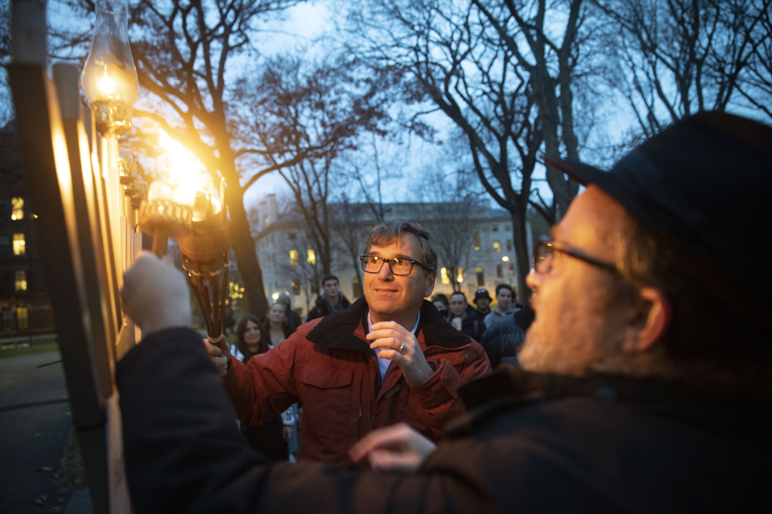 Kennedy School Professor Jason Furman lights the menorah outside Widener Library with Rabbi Hirschy Zarchi.