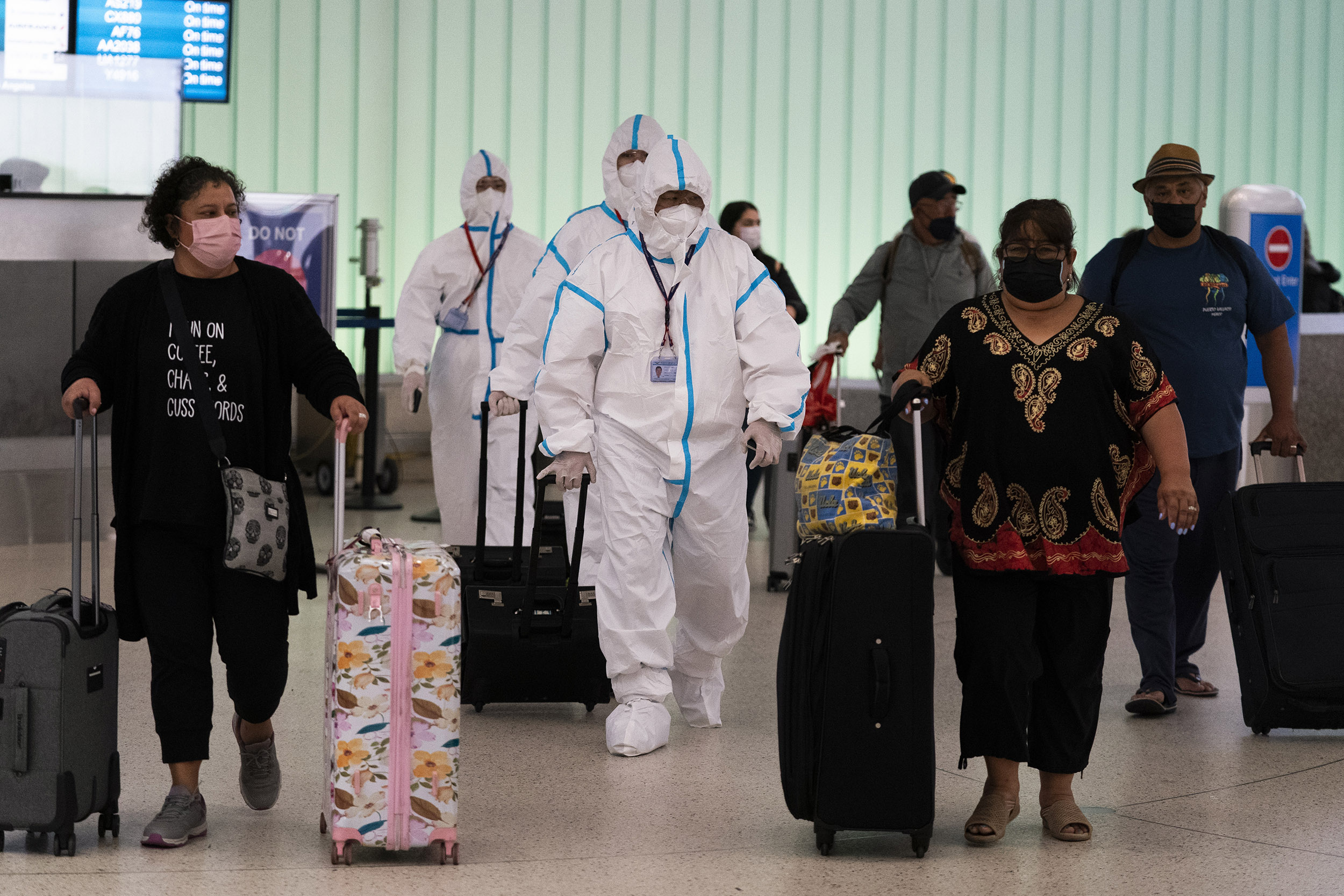 Flight crew members in hazmat suits walk through LAX.