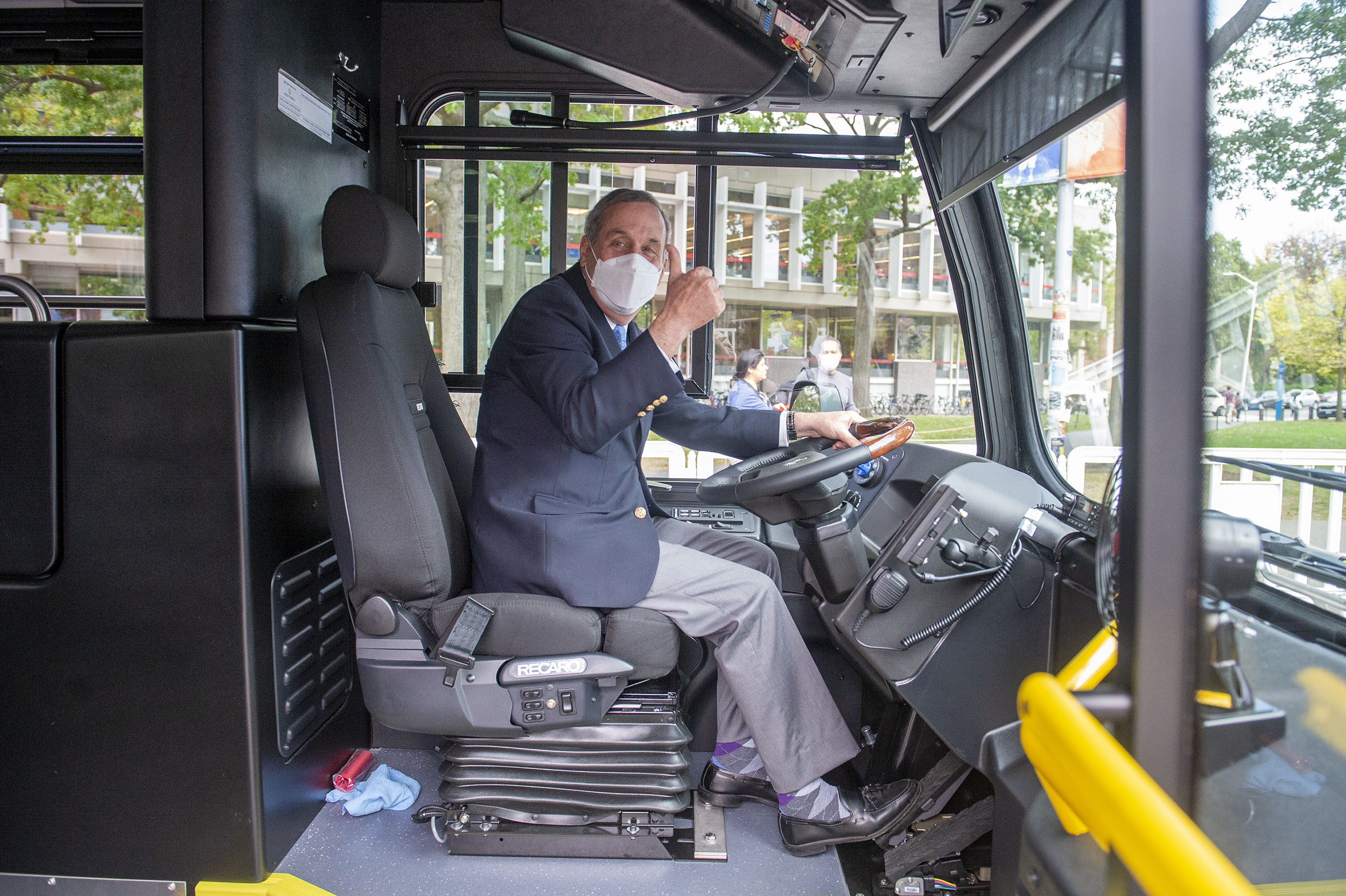 Larry Bacow in driver's seat of electric shuttle bus.