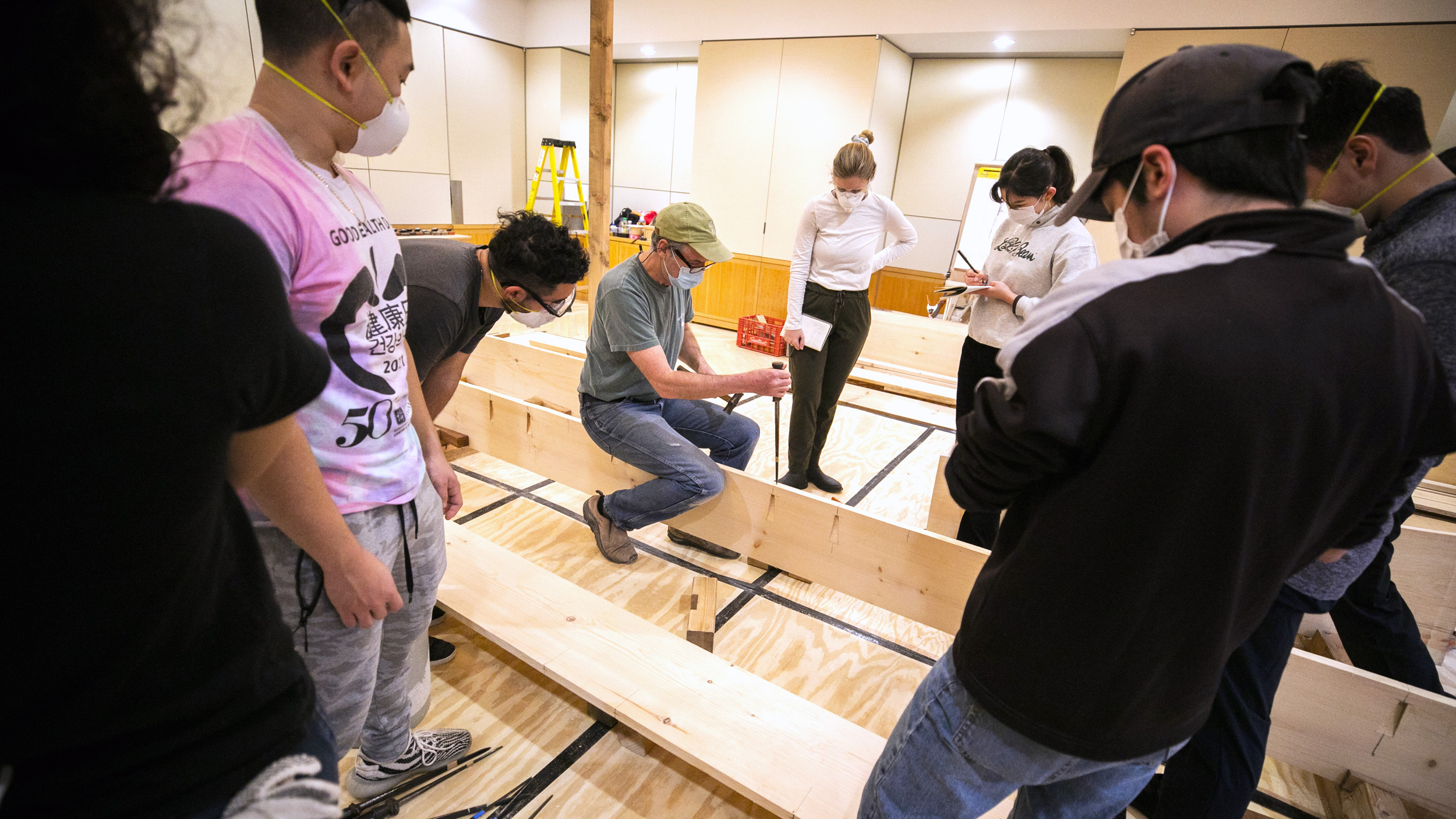 Students gather around instructor Douglas Brooks as they build a Japanese river skiff.
