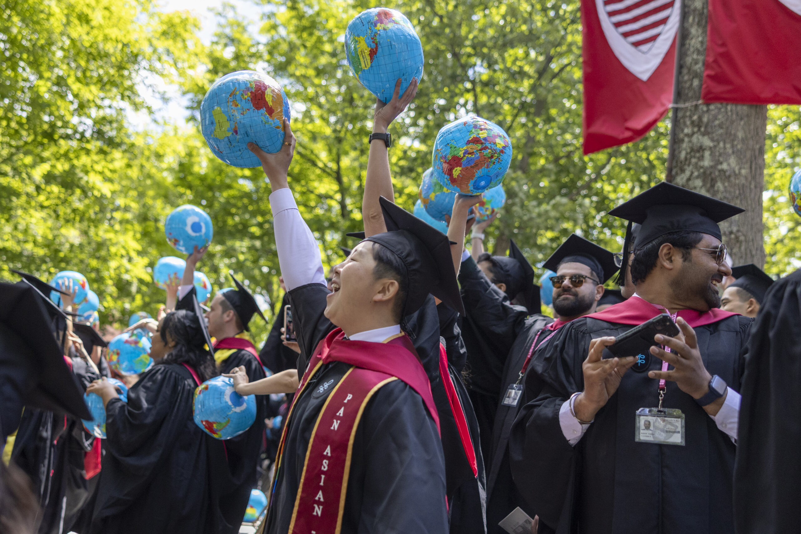 Graduates hold globes in Harvard Yard.