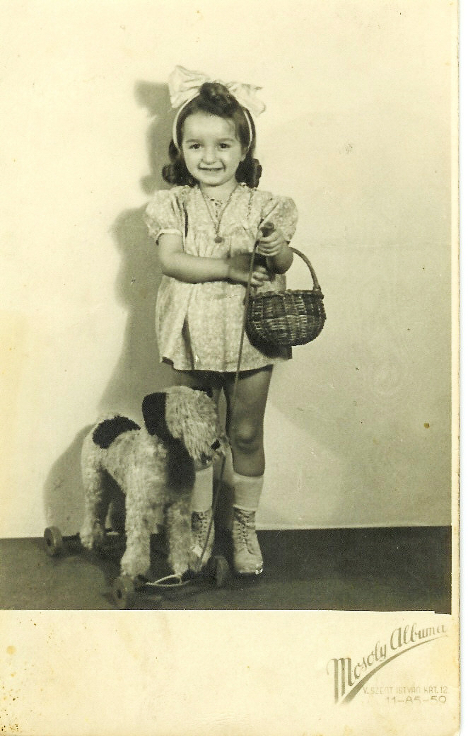 Black-and-white childhood portrait of Susan Suleiman posing with a dog with a bow in her hair.