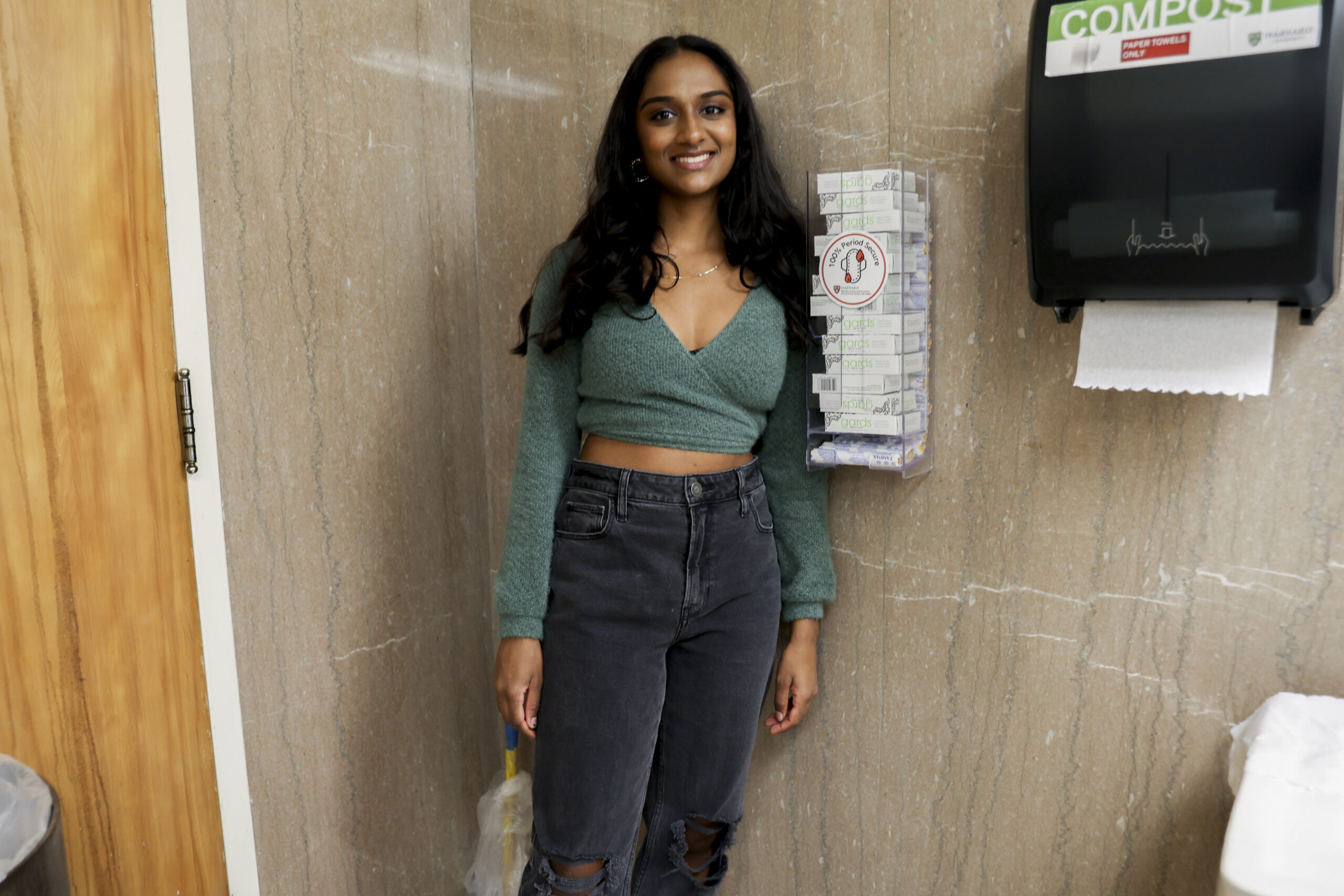 Shruthi Kumar with a newly installed menstrual product dispenser in Lamont Library.