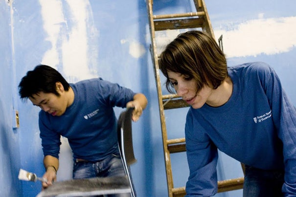 Joseph Lai '14 and Iulia Cojocarv '11 don blue Harvard public service T-shirts while painting over the blue rooms of the Cambridge Community Center.