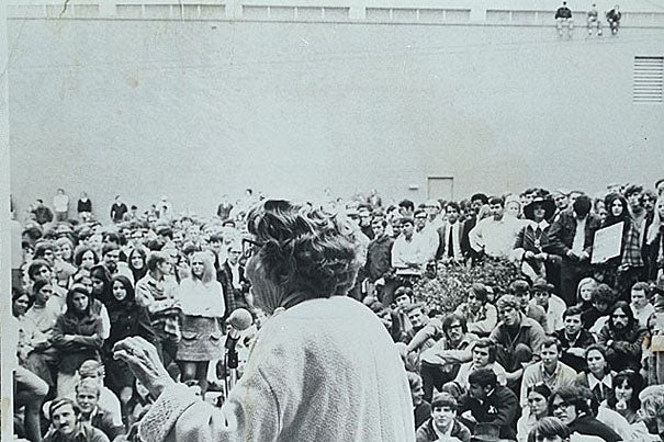 1970: Jeannette Rankin, standing behind a microphone, addressing a large group of University of Georgia students (including three people seated on a university building roof). 