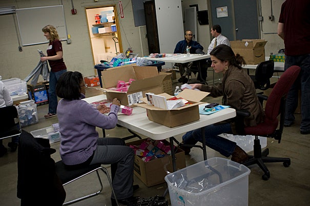 Harvard Public Affairs and Communications staff members turn stacks of math and language arts games into 1,800 SmartTALK learning kits in a warehouse near HASI’s Allston headquarters.