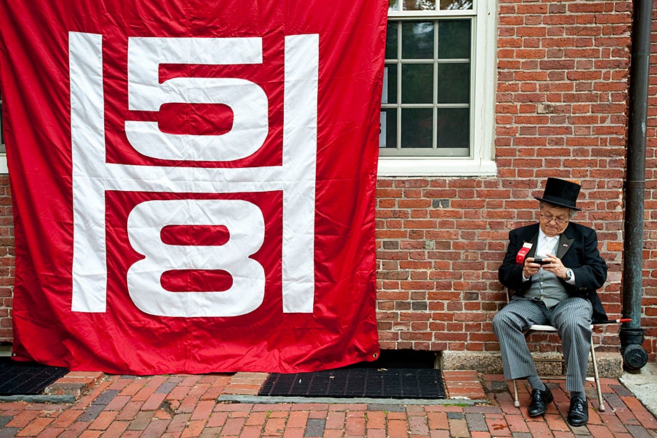 Wallace Sisson of Milton, Mass., consults his phone while volunteering as a member of the Committee for the Happy Observation of Commencement. Kristyn Ulanday/Harvard Staff Photographer