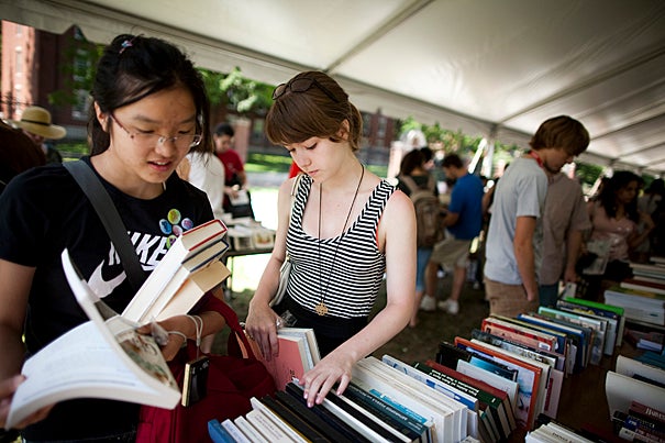 At a recycling exchange under a tent in front of Harvard's Science Center,  Rosalind He (left) and Grace Imeson pore over stacks of free books.