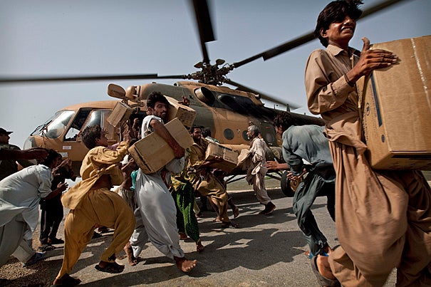Pakistanis carry boxes of food from an Afghan army helicopter after it landed on a road to deliver emergency food aid in a flooded area of Baluchistan Province, southern Pakistan. According to Harvard water engineer John Briscoe, Pakistan’s long-term water security requires institutional renewal and new infrastructure, including new dams, on the Indus River.