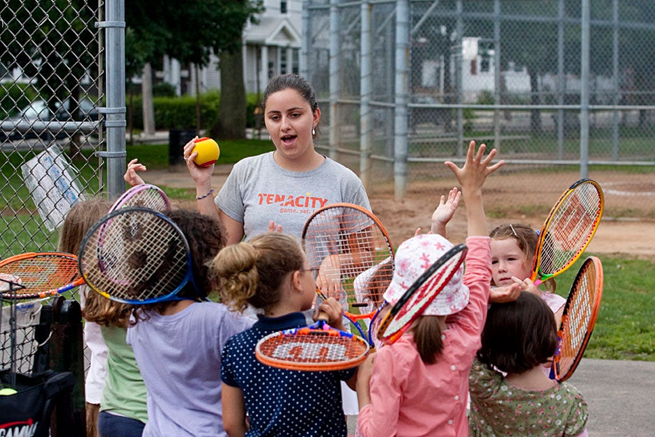 A Harvard Allston Summer Corps teen works with campers at Tenacity, a Boston nonprofit that teaches tennis, literacy, and life skills to kids in after-school and summer programs. Jon Chase/Harvard Staff Photographer