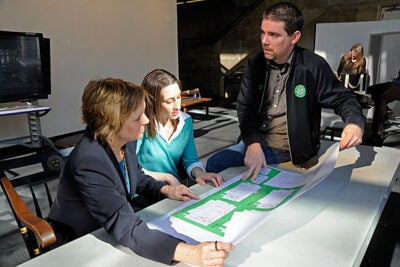 Graduate School of Design staffers Kate Eaton (center) and Trevor O'Brien look over plans showing Gund Hall green initiatives with Laura Snowdon (left), dean of students.