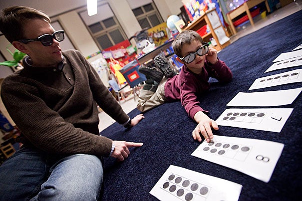 Sean Andersson (left) works on a math problem called "X-ray vision" with his son Ethan, 5, at the Gardner Pilot Academy. Math Night was the latest of Harvard’s many collaborative efforts with the school.