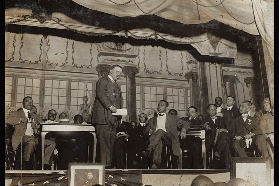 Booker T. Washington (center, right) listens to Theodore Roosevelt (center, left) deliver a speech on stage in Tuskegee, Alabama. On June 24, 1896, Washington became the first African American to receive an honorary degree from Harvard University. Photo by American Press Association. Photo credit: Theodore Roosevelt Collection (560.52 1905-168)