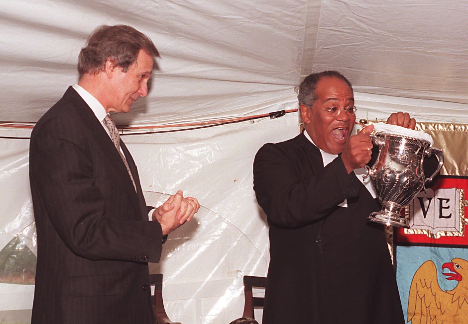 Harvard President Neil L. Rudenstine presents a silver urn to the Rev. Peter J. Gomes at "A Collation on the Delta," a celebration on Nov. 14, 1999 honoring Gomes for his 25 years as minister in the Memorial Church. Photo by Marc Halevi