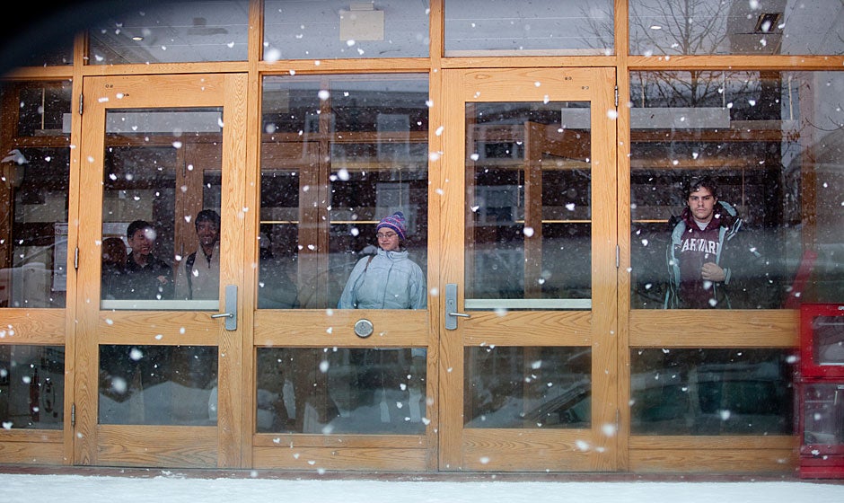 Students wait in the foyer for the shuttle as snow falls at Currier House. Rose Lincoln/Harvard Staff Photographer