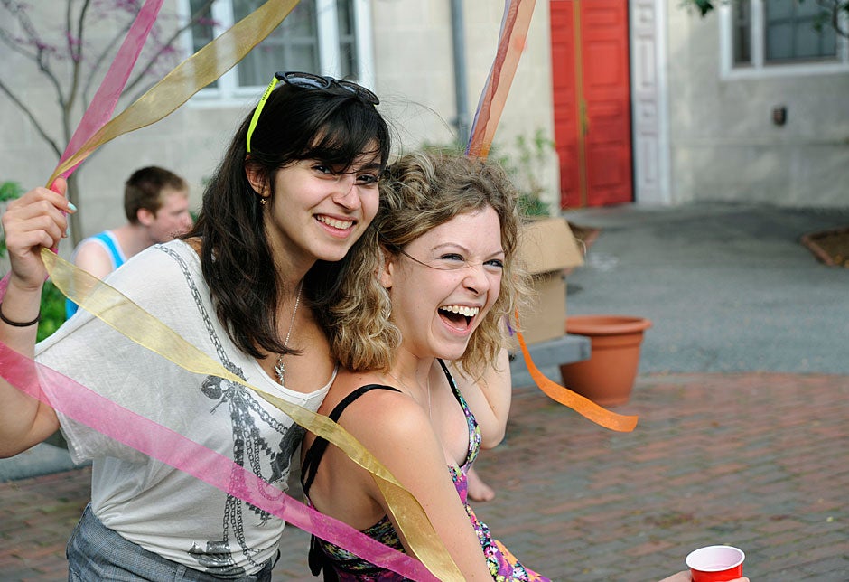Liora Simozar '13 (left) and Tess Hellgren '11 share a laugh while getting tangled up in wind-blown ribbons in the courtyard during festivities at the annual Dunster House goat roast. Jon Chase/Harvard Staff Photographer