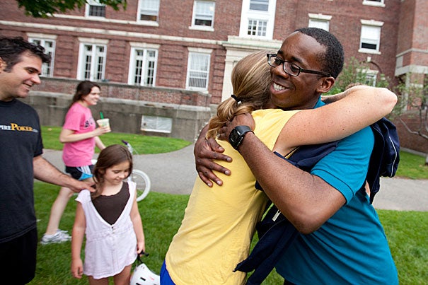Acky Uzosike '13 (right) is welcomed back to campus by Allston Burr Resident Dean Jill Constantino at Cabot House during move-in day. Constantino's husband, Michael Baran, and their daughter, Rio, age 7, are in the background.