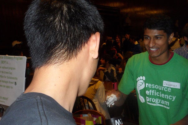 FAS Green Program student rep Dewahar Senthoor '13 scoops ice cream into a freshman's reusable mug.