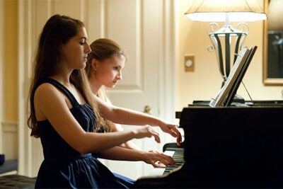 Twins Danielle '14 (left) and Arielle Rabinowitz '14 perform a piano duet before a black tie High Table dinner at Lowell House. 