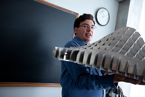 Joseph K. Blitzstein, a new professor of statistics and an award-winning teacher, holds a two-dimensional normal distribution built by Fred Mosteller, who founded the department in 1957. Bending it illustrates different correlations. 