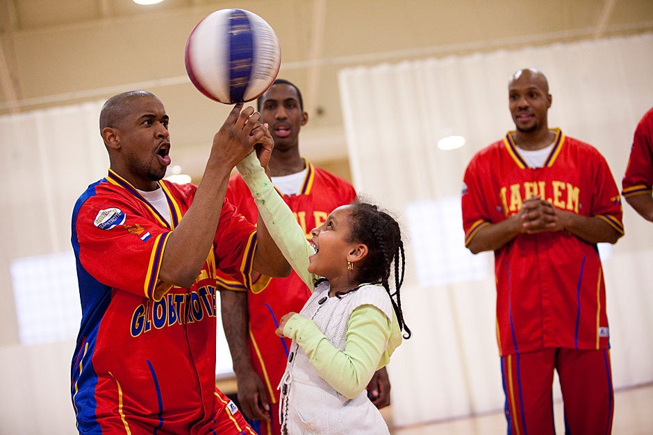 Spinning balls and Harlem Globetrotters go together. Globetrotter "Scooter" (from left) helps student Betunia Zelanlem learn to master the trick. Stephanie Mitchell/Harvard Staff Photographer