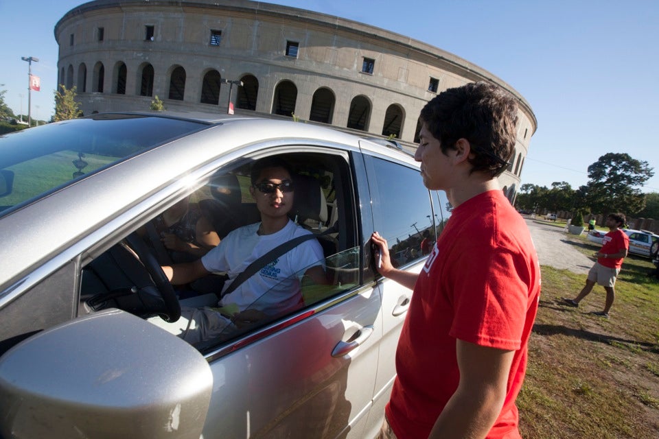 Kevin Hernandez `13 greets Jack Huang `16 (left) at Harvard Stadium as cars line up to enter Harvard Yard for the annual tradition of Move-In Day.