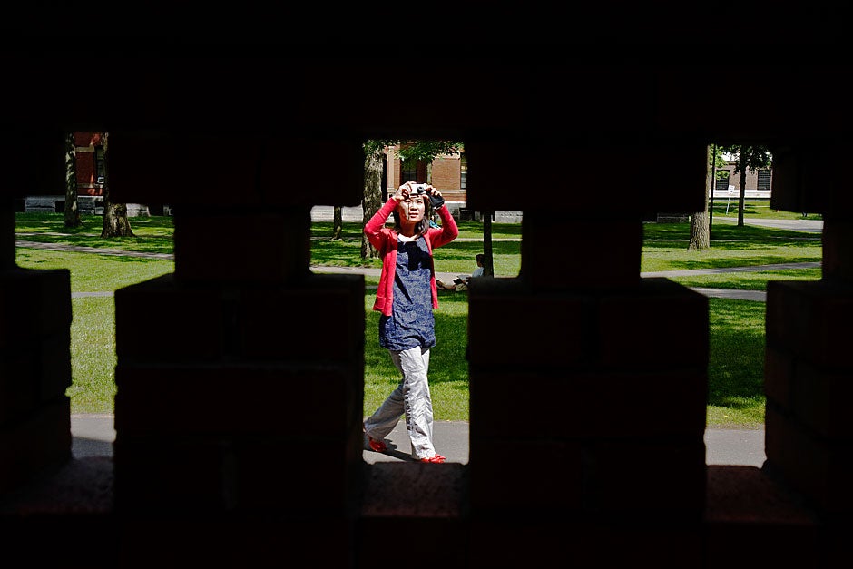 Beatrice Chu, a visitor from Hong Kong, crosses these crosses in the brick wall outside Matthews Hall. Jon Chase/Harvard Staff Photographer