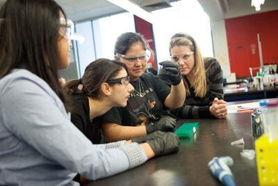 Chelsea High School students Neris Yanes (left) and Karina Perez (second from right) work with research assistant Alia Qatarneh and Chelsea High teacher Melissa Puopolo (right) on a lab exercise involving RFP-expressing bacteria.