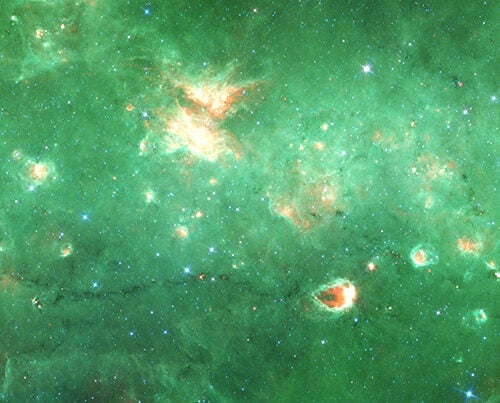 Researchers have identified the first “bone” of the Milky Way — a long tendril of dust and gas that appears dark in this infrared image from the Spitzer Space Telescope. Running horizontally along this image, the “bone” is more than 300 light-years long.