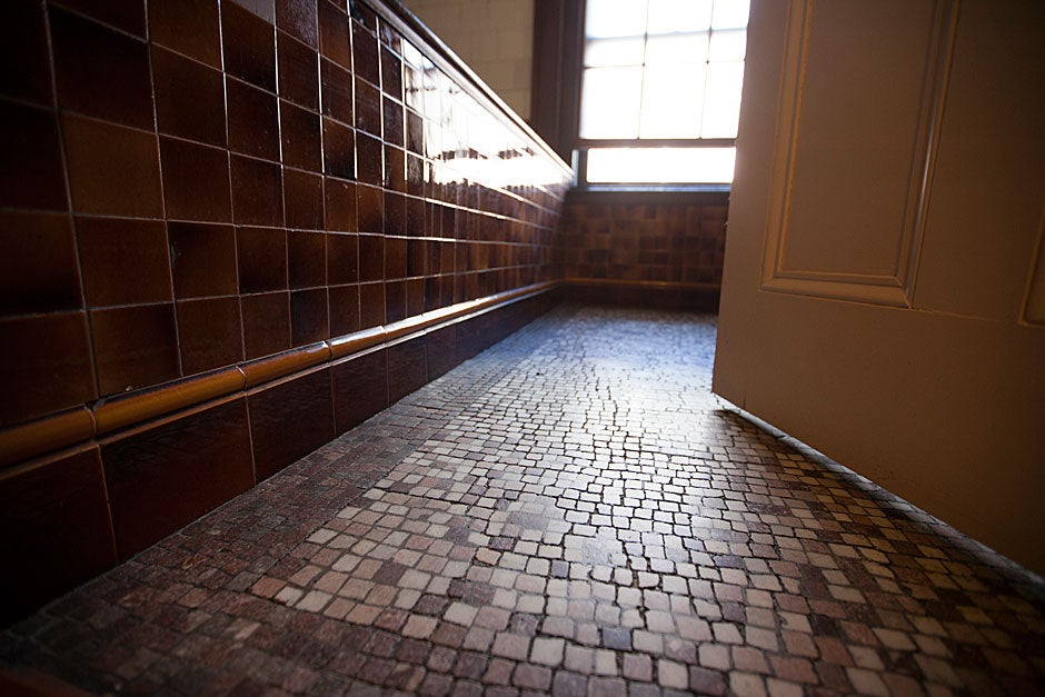 Worn and random brown tesserae are patterned on the floor of the 1891 bathroom.