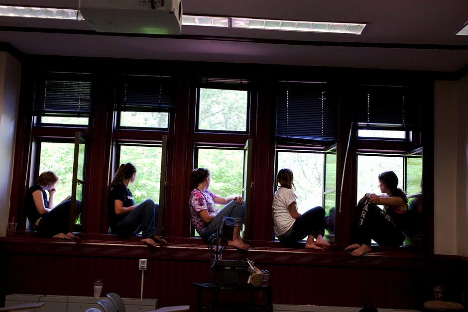 Miranda Shugars '14 (from left), Steph Hadley '15, Kathryn Reed '13, Leonie Oostrom '15, and Christine Mansour '15, all members of dorm crew, take a break to watch the ceremony from the windows of Sever Hall during the 2012 Commencement. Rose Lincoln/Harvard Staff Photographer
