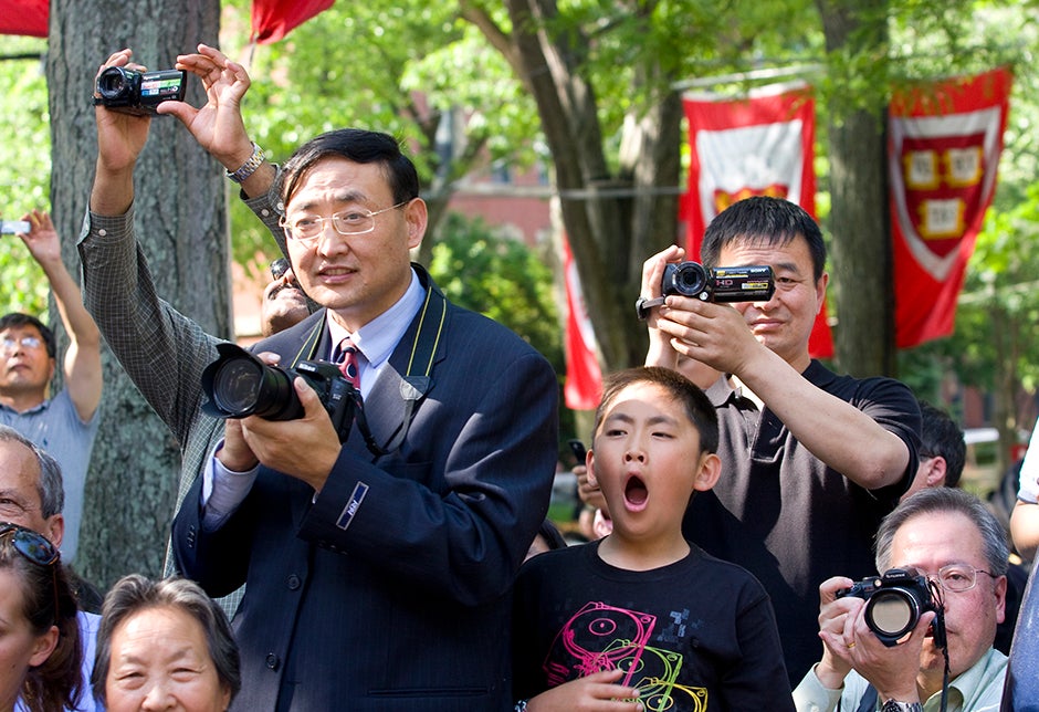 John Xi (left), from Chicago, father of Joy Xi '09, joins other parents in photographing their kids during the Class of 2009 official class photo, while son Matt, age 10, can't stifle a yawn during the proceedings. Jon Chase/Harvard Staff Photographer