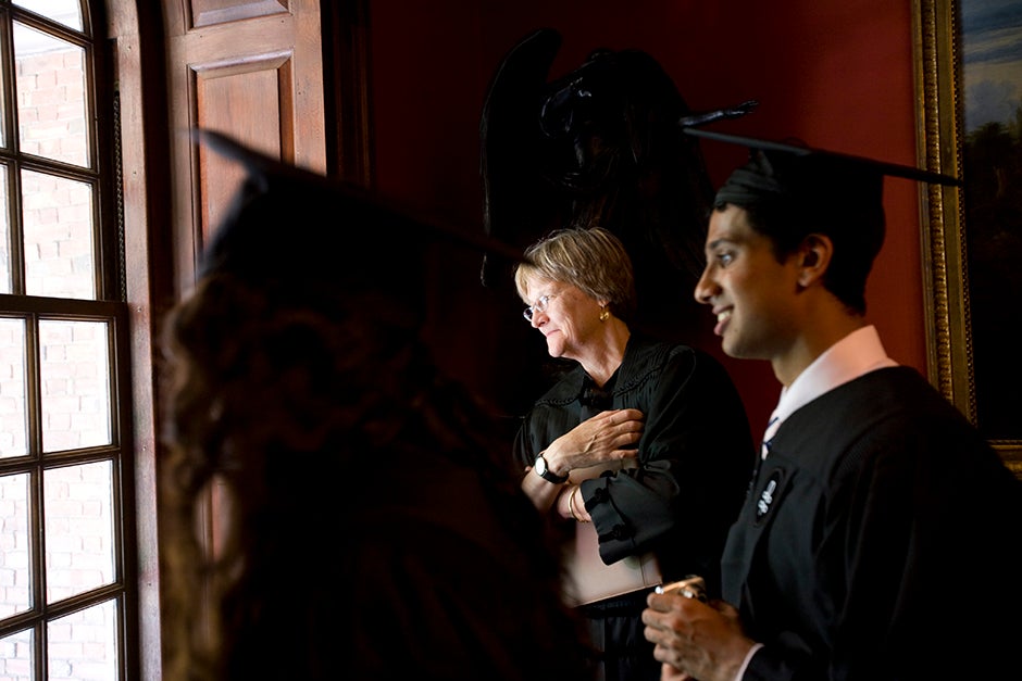 Harvard University President Drew Faust (from center) and Ravi Parikh look out the window watching the graduates line up to process into Memorial Church for the 2009 Baccalaureate Service. Stephanie Mitchell/Harvard Staff Photographer